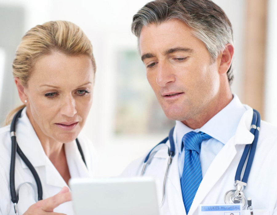 Two healthcare professionals in white coats reviewing information together on a tablet, representing clinical decision-making and career evaluation in healthcare